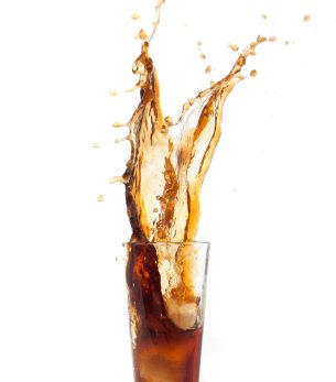 bebida marron cayendo un hielo dentro